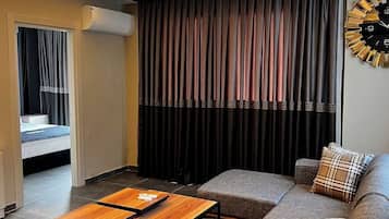 Suite familiare, 1 letto queen con divano letto, balcone, vista città | Area soggiorno | TV 64 pollici con canali digitali, caminetto