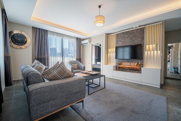 A modern living room with a sofa, coffee table, and a fireplace. - LIMONOTTO SUIT OTEL (Mersin)