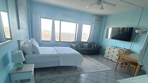 A bedroom with a bed, a desk, a chair, a television, and a ceiling fan. - Oceanfront High Point North Studio M8 Just Steps to the Beach! (Ocean City)