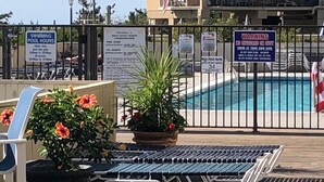 A swimming pool area with lounge chairs, a potted plant, and multiple signs including one for pool hours and a warning sign. - Oceanfront High Point North Studio M8 Just Steps to the Beach! (Ocean City)