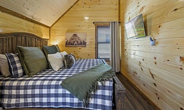 Une chambre confortable dans un chalet en bois, avec une couette à carreaux, des oreillers et une couverture.