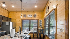 A wooden interior with a long dining table, chairs, and a kitchen area. - Charming Pet Friendly 3 Bedroom Chalet in Pigeon Forge with heated pool (Pigeon Forge)
