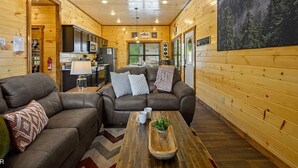 A cozy cabin interior with a living area featuring two sofas, a coffee table, and a kitchen area with modern appliances. - Charming Pet Friendly 3 Bedroom Chalet in Pigeon Forge with heated pool (Pigeon Forge)