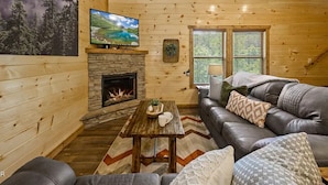 A cozy cabin interior with a fireplace, a large television, and a comfortable seating area. - Charming Pet Friendly 3 Bedroom Chalet in Pigeon Forge with heated pool (Pigeon Forge)