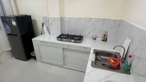 A compact kitchen with a gas stove, a sink, and a refrigerator.