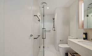 A modern bathroom with a glass shower enclosure, a toilet, and a sink with a mirror above it. - Facehome QWR (Brisbane)