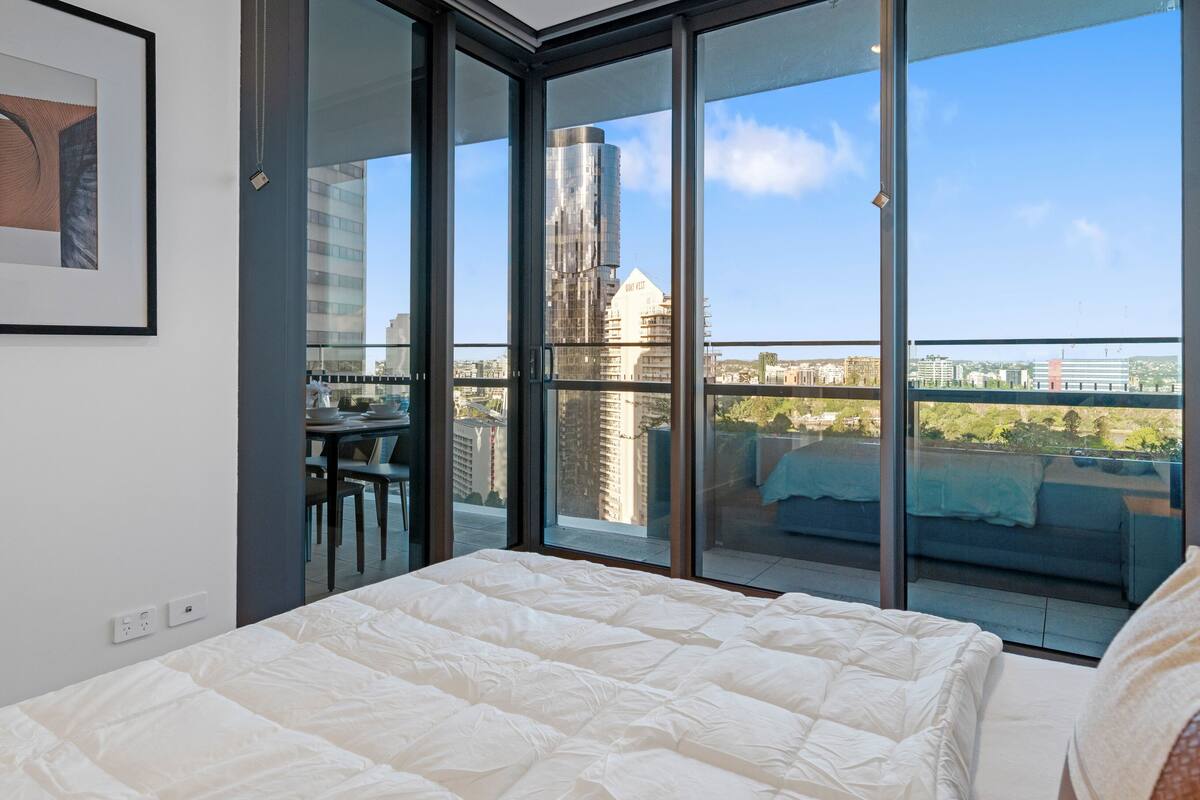 Ein Schlafzimmer mit einem großen Bett, einem Balkon mit Blick auf die Stadt und einem Essbereich mit Tisch und Stühlen.