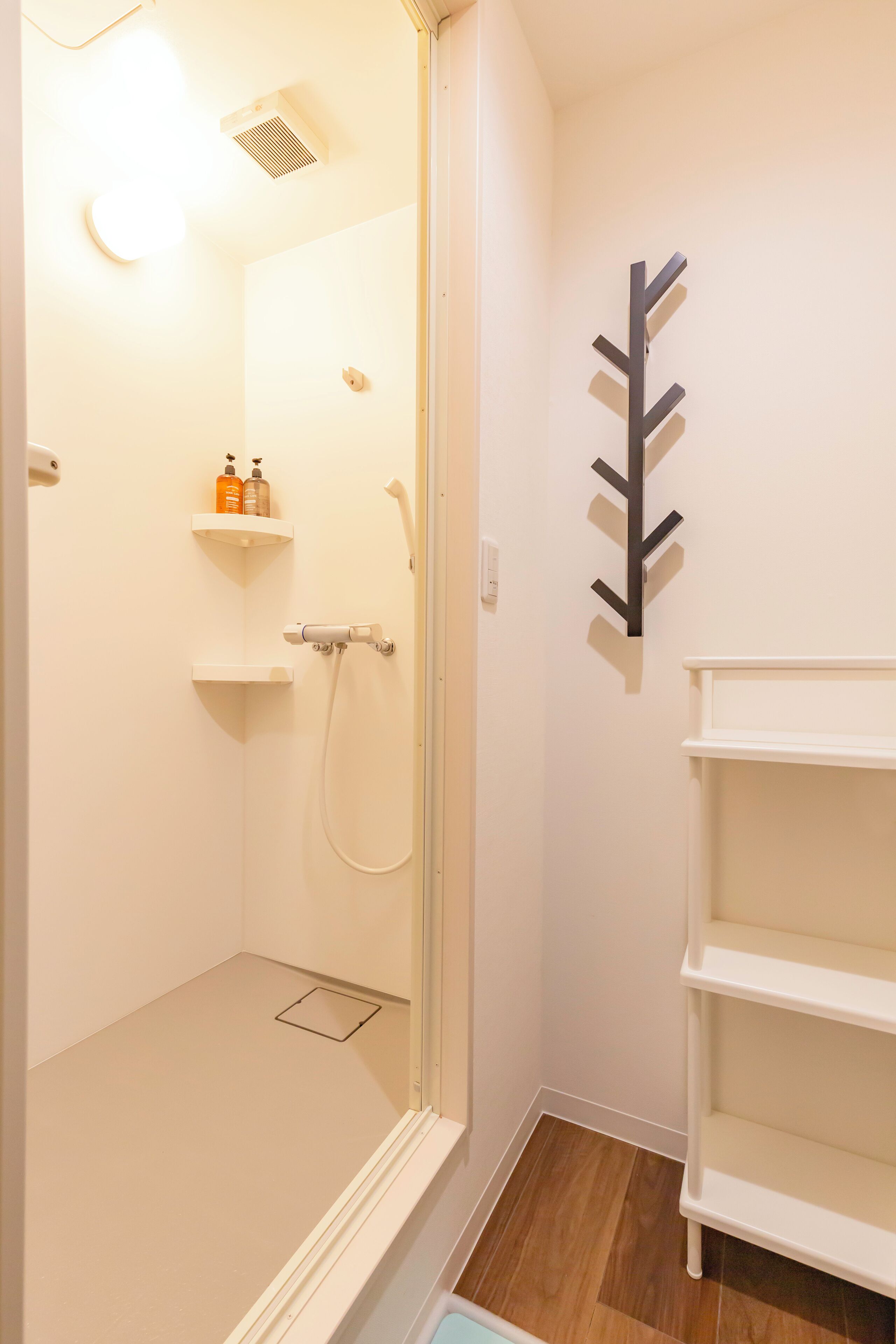 A bathroom with a shower, a toilet, and a sink. There are two shelves with toiletries.