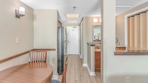 A hotel hallway with a wooden bench, a refrigerator, a door, and a bathroom visible through an open door. - Oceanfront w/ Indoor Waterparks at Dunes Village! (Myrtle Beach)