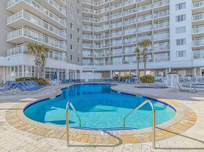 A hotel with a swimming pool surrounded by lounge chairs and a multi-story building with balconies. - Luxe Oceanfront @ Seawatch Resort! (Horry County)