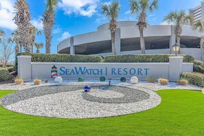 Schild des SeaWatch Resort mit kreisförmigem Garten und Palmen.