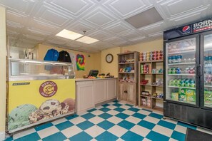 Eine Speisehalle mit kariertem Boden, einem Kühlschrank mit Pepsi und einer Theke mit Schild der Mayfield Dairy Farms.