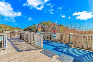 A wooden boardwalk leading to a pool area with accessible pathways and decorative totem poles. - Luxe Oceanfront @ Seawatch Resort! (Horry County)