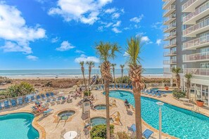 Ein Hotelpoolbereich mit mehreren Pools, Palmen und Blick auf den Strand.
