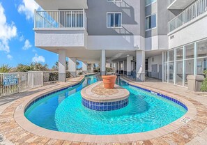 Une piscine avec une fontaine, un espace abrité et un bâtiment doté de balcons.