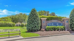 Une entrée bien entretenue, avec une enseigne indiquant « Willow Bend », un mur en briques et un banc.