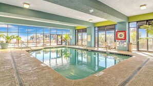 Una piscina interior con paredes de vidrio transparente, un letrero de salvavidas y vistas al exterior.