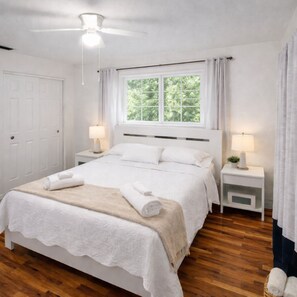 A neatly arranged bedroom with a large bed, two bedside tables with lamps, a ceiling fan, and a window with curtains. - Fort Myers Shores quiet, 3-BR/2 BA renovated pet-friendly House (Fort Myers)