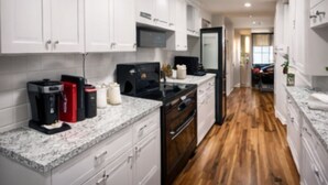 A modern kitchen with white cabinets, a black stove, and a granite countertop. - Fort Myers Shores quiet, 3-BR/2 BA renovated pet-friendly House (Fort Myers)