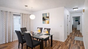 A dining area with a glass table, black chairs, and a pendant light. - Fort Myers Shores quiet, 3-BR/2 BA renovated pet-friendly House (Fort Myers)