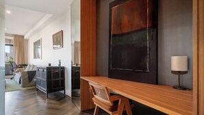 A modern living room with a wooden desk, a sofa, and a large abstract painting on the wall.