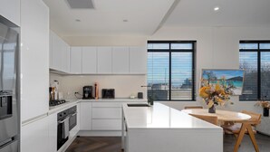 A modern kitchen with white cabinetry, a central island, and a dining area with a wooden table and chairs.