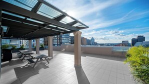 A rooftop terrace with outdoor seating and a city skyline view.
