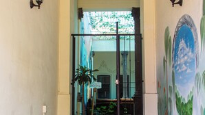 A hallway with steps leading to a room, decorated with wall art and potted plants. - El Pinche Hostal (Guadalajara)