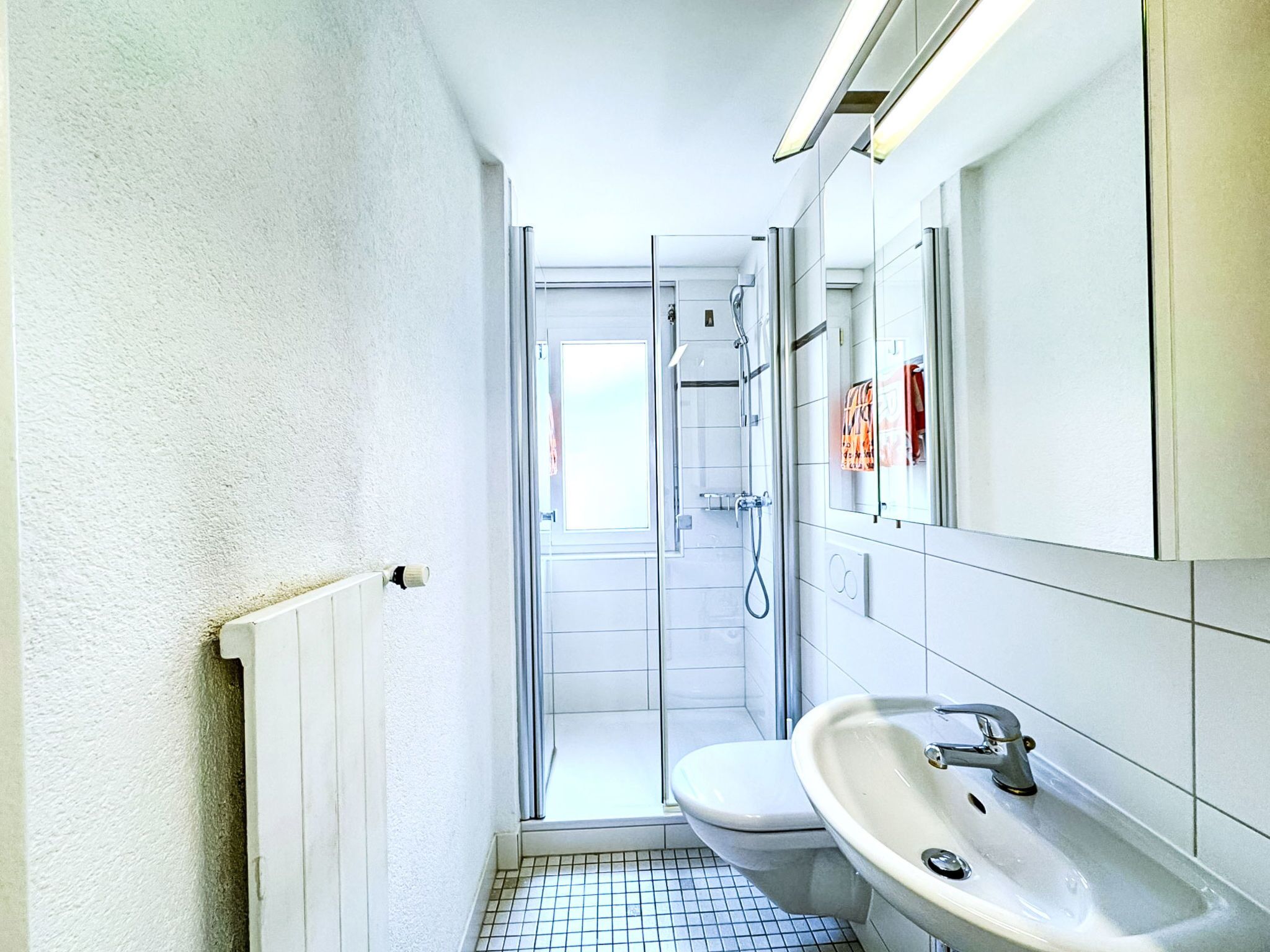A compact bathroom with a toilet, sink, and shower.