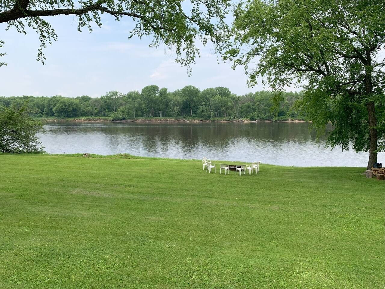 A grassy area with a lake and trees in the background.