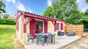 A small, red-roofed building with a patio area featuring a table and chairs.