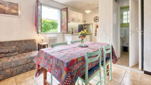 A cozy room with a patterned tablecloth, a sofa, and a view of a garden through a window.