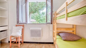 Habitación con literas, ventana, radiador y una silla.
