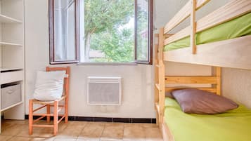 A bunk bed room with a window, a radiator, and a chair.
