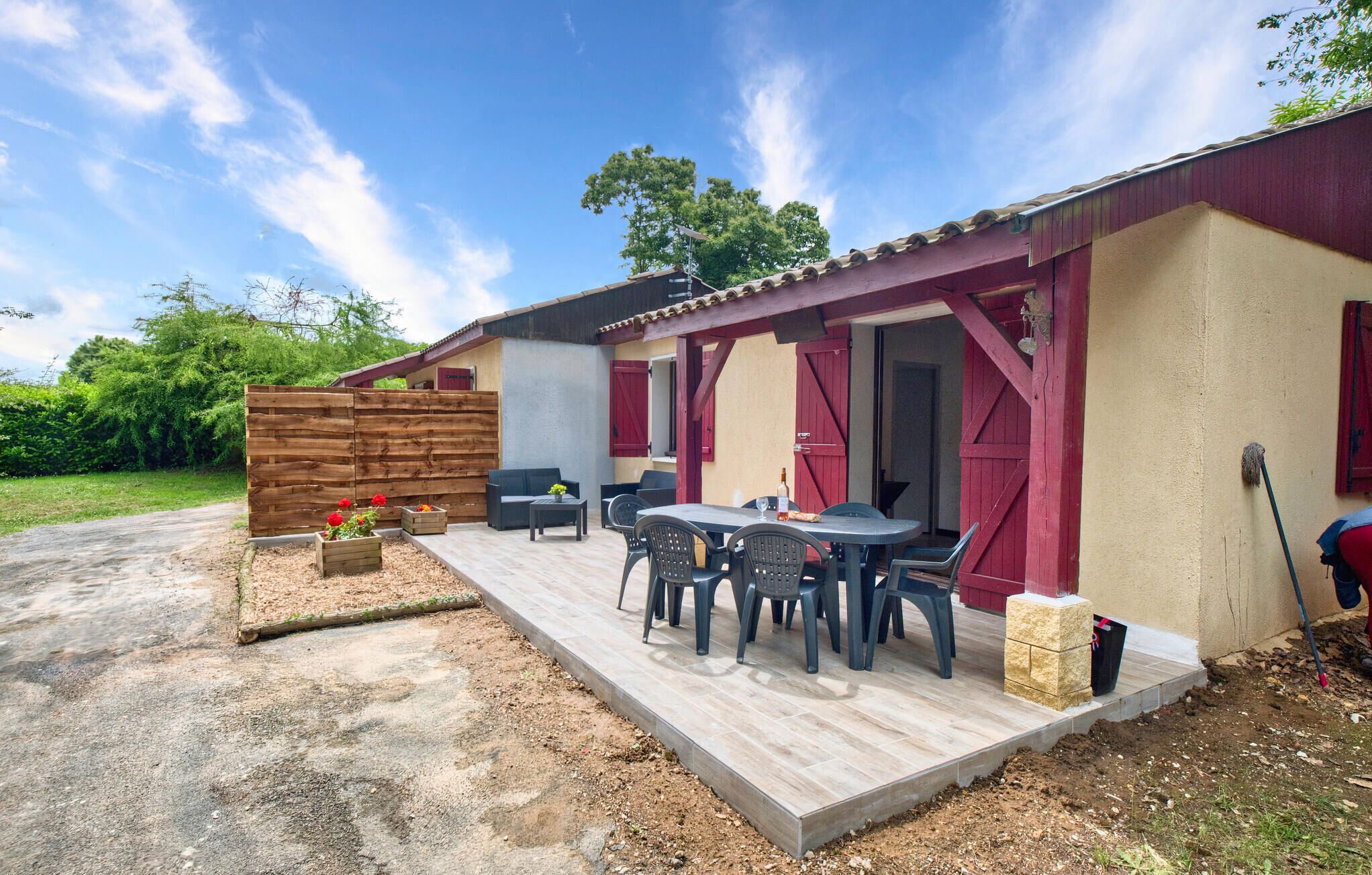 A covered patio area with outdoor seating, a wooden fence, and a table with chairs.