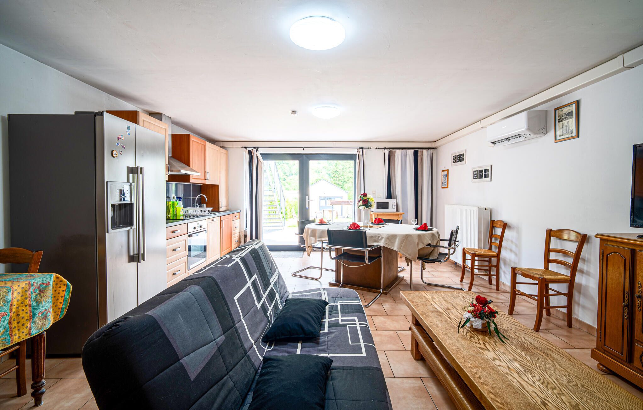 A compact living space with a sofa, dining table, kitchen area, and a view through the door.