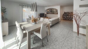 A modern living room with a dining area, a sofa, a TV, and a decorative plant. - Cozy home in Cessenon sur Orb (Cessenon sur Orb)