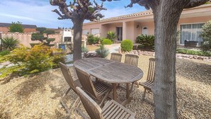 An outdoor patio with a wooden table and chairs, surrounded by gravel and various plants. - Cozy home in Cessenon sur Orb (Cessenon sur Orb)