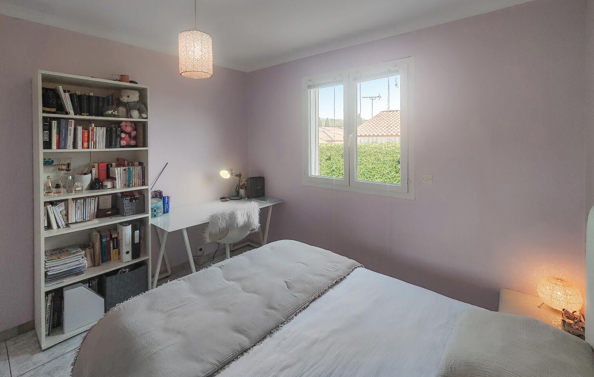 Une chambre à coucher avec un lit, un bureau, une bibliothèque et une fenêtre.
