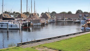 A marina with several boats docked, a grassy area in the foreground, and buildings in the background. - 5 bedroom amazing home in Idskenhuizen (Idskenhuizen)