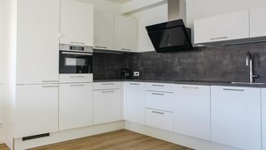 A modern kitchen with white cabinetry, a black countertop, and a built-in oven.