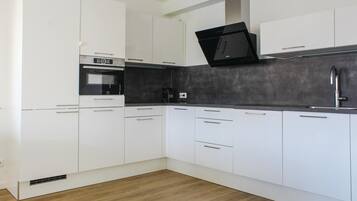 Een moderne keuken met witte kastjes, een zwart aanrecht en een inbouwoven.