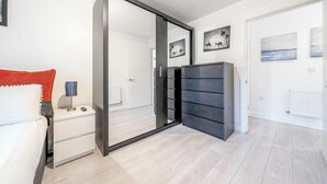 A modern bedroom with a sliding door, a bedside table with a lamp, and a wardrobe. - Luxury Central London Balcony 1-Bed Apt w/ Parking (London)