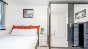 A modern bedroom with a bed, nightstand, and a sliding closet door. - Luxury Central London Balcony 1-Bed Apt w/ Parking (London)