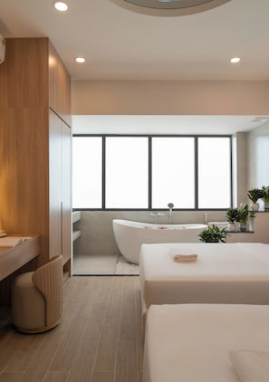 Een moderne badkamer met een vrijstaand bad, een groot raam en een houten wastafelmeubel.