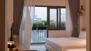 A hotel room with a bed, a desk with a cup, and a view of the city through large windows. - The Cozy Inn Ho Chi Minh (Ho Chi Minh City)