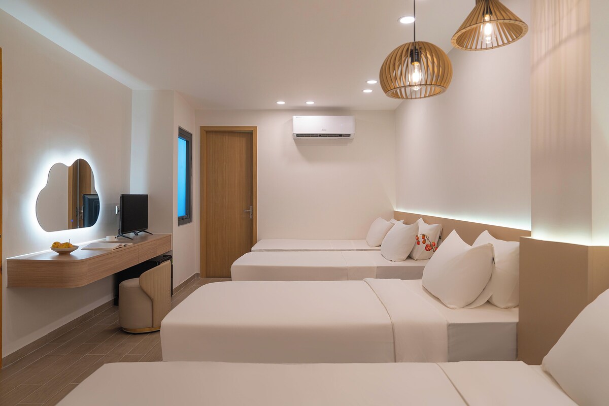 A modern hotel room with a bed, bedside tables, a mirror, and a wall-mounted air conditioner.