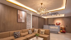 A modern reception area with a sofa, a coffee table, and a reception desk labeled "The Cozy Inn". - The Cozy Inn Ho Chi Minh (Ho Chi Minh City)