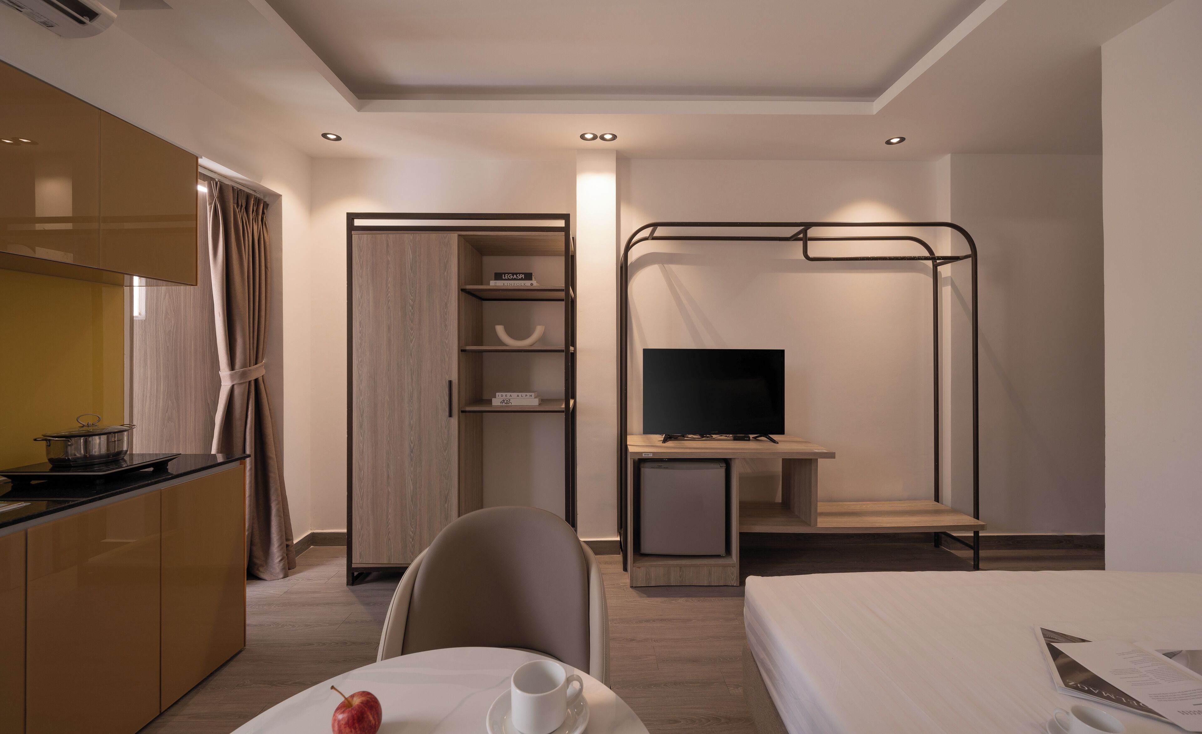 Habitación de hotel compacta con kitchenette, cama, televisión y un pequeño escritorio.