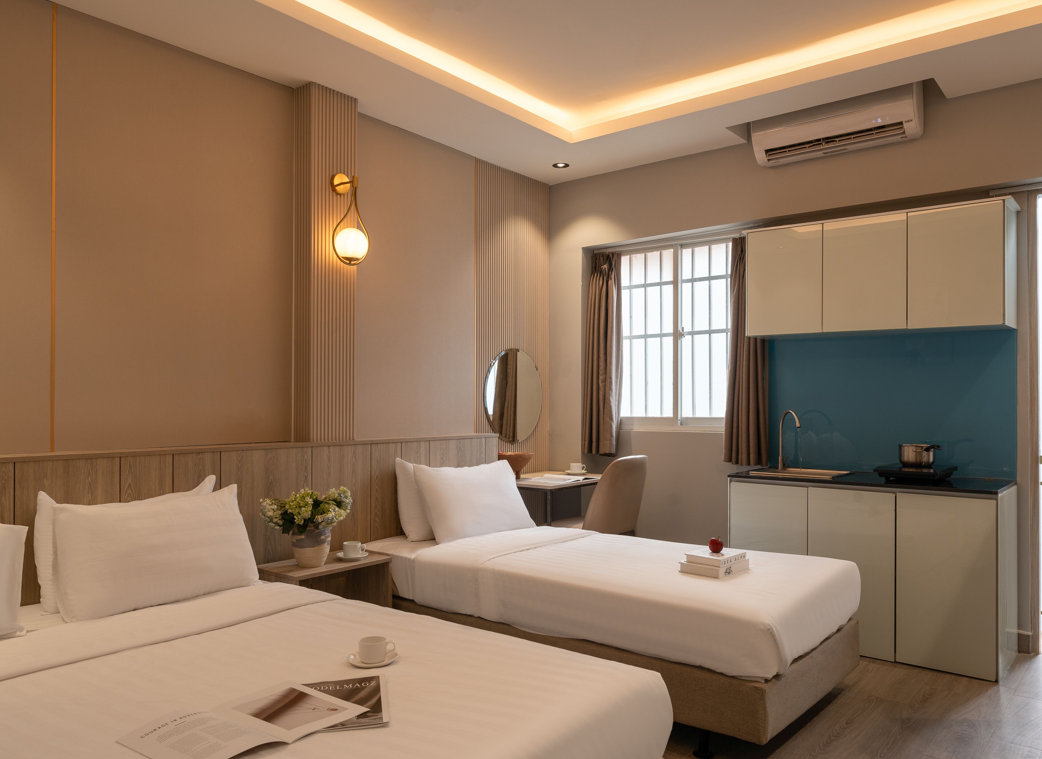 Une chambre d’hôtel avec deux lits, un bureau, une fenêtre avec des rideaux et une kitchenette.